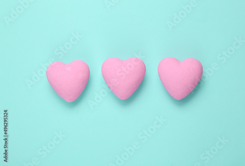 Three pink hearts on blue background. Minimal love still life