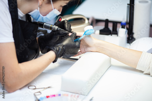 Manicure master removes cuticles with electric file machine on female hand in nail salon © splitov27