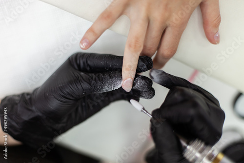 Manicurist professional files  shaping false nails for manicure in a nail salon