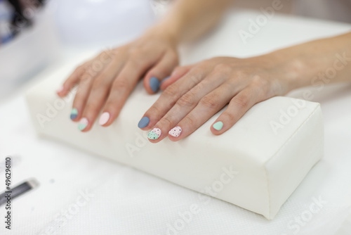 Beautiful female hands with pastel color manicure on a towel in a nail salon
