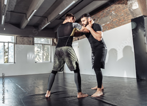 Fototapeta Naklejka Na Ścianę i Meble -  Sparring training of two athletic mma fighters in the gym. Martial arts, Wrestling