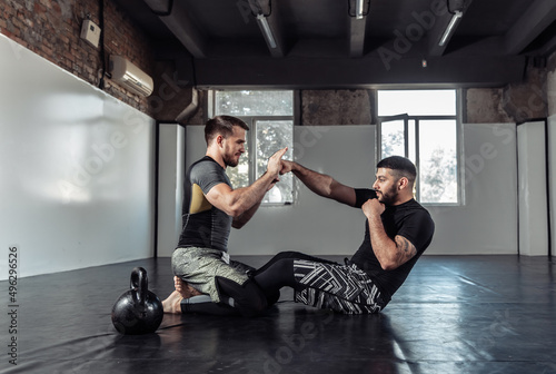 Two male fighters train muscles in a sports hall