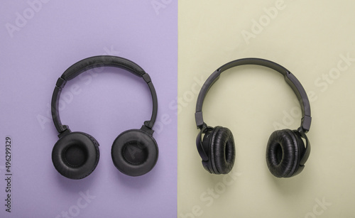 Two pairs of black wireless stereo headphones on yellow purple background