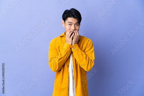 Young Chinese man isolated on purple background happy and smiling covering mouth with hands