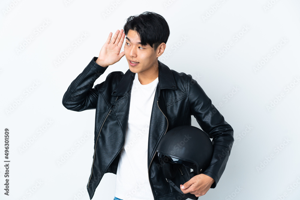 Chinese man with a motorcycle helmet isolated on white background listening to something by putting hand on the ear Chinese man with a motorcycle helmet isolated on white background listening to something by putting hand on the ear