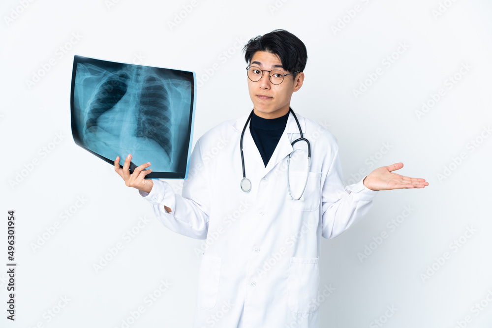 Young Chinese doctor man holding radiography isolated on white background having doubts while raising hands