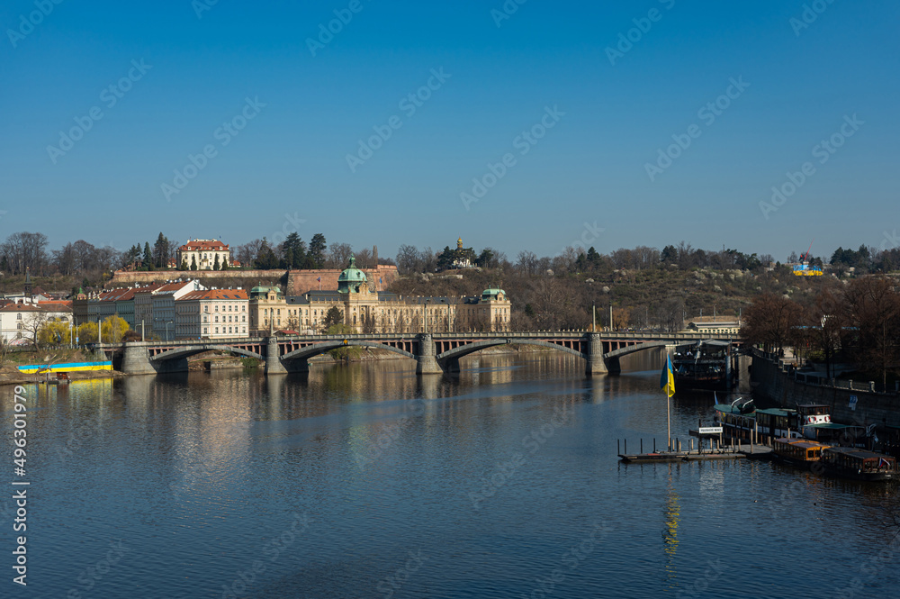 Obraz premium Prague, Czech Republic view of the Vltava river on the Manes bridge. The end of March. River banks in Ukrainian flags.