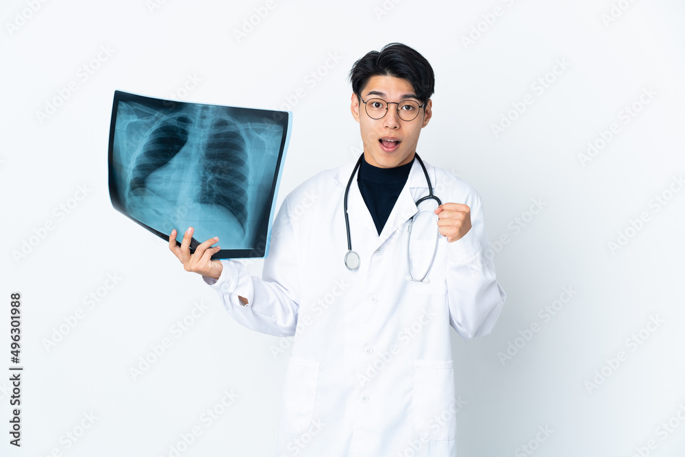 Young Chinese doctor man holding radiography isolated on white background celebrating a victory in winner position