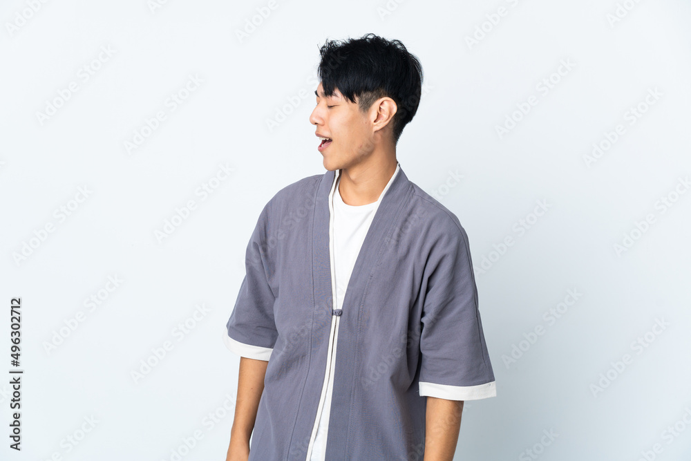 Young Chinese man isolated on white background laughing in lateral position Young Chinese man isolated on white background laughing in lateral position