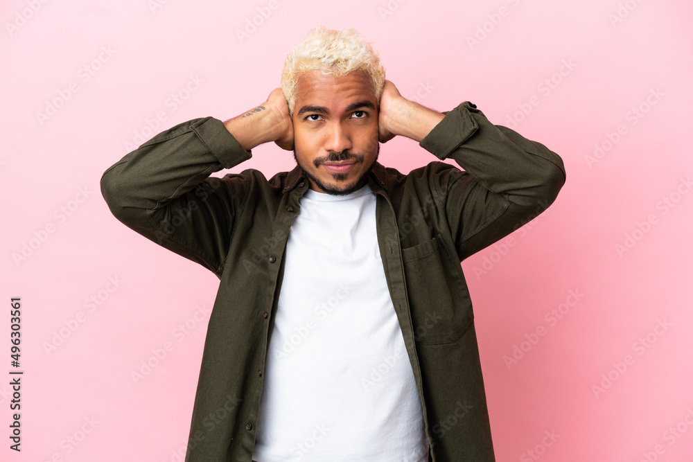 Young Colombian handsome man isolated on pink background frustrated and covering ears Young Colombian handsome man isolated on pink background frustrated and covering ears