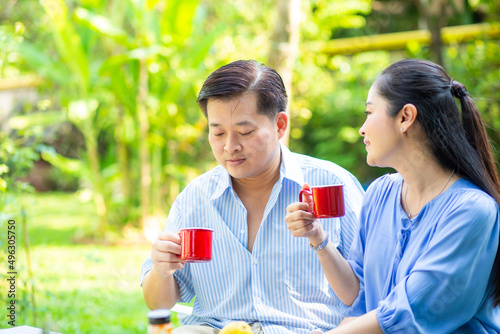 Happy asian senior couple taking with coffee drink in green garden