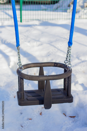 Swing on the children playground in winter with snow