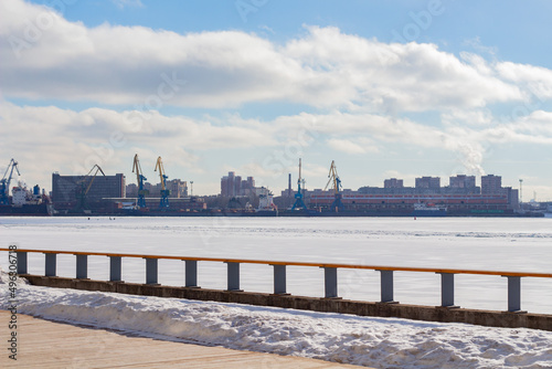 View of the port with cranes in winter from the river bank, industrial area