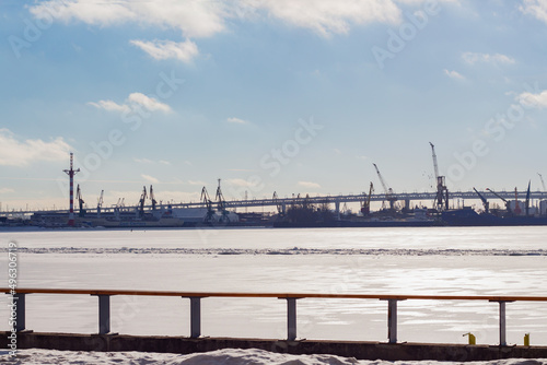 View of the port with cranes in winter from the river bank, industrial area