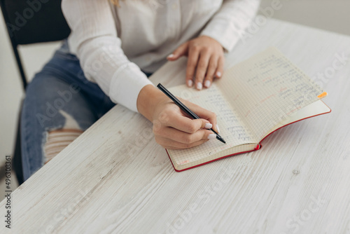 Beautiful student girl makes notes in a notebook