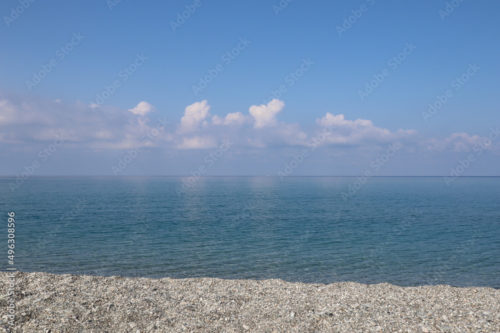 Obraz premium Sea and sky, beach and clear blue sea and clear sky with white clouds on a sunny morning. Calabria, Tyrrhenian coast, Italy