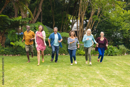 Carefree multiracial senior male and female friends running in backyard