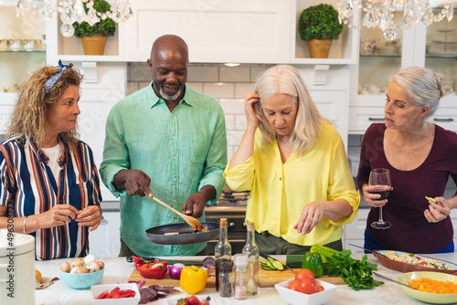 Multiracial senior women and man preparing food together in kitchen at home