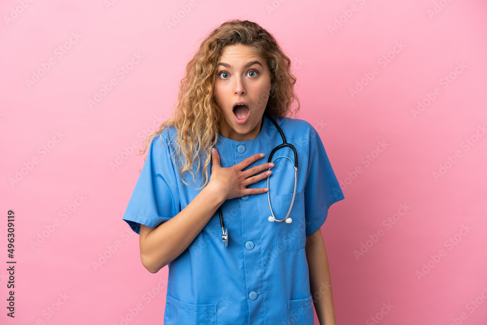 Young surgeon doctor woman isolated on pink background surprised and shocked while looking right