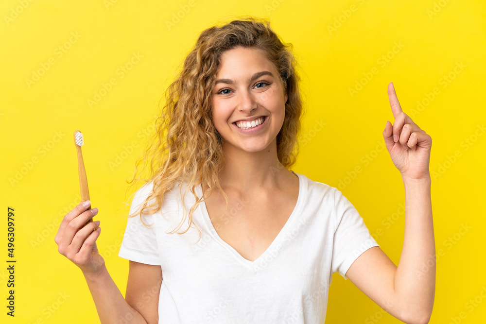 Young caucasian woman holding a brushing teeth isolated on yellow background pointing up a great idea Young caucasian woman holding a brushing teeth isolated on yellow background pointing up a great idea