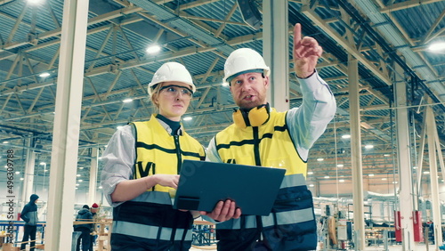 Two factory specialists are smiling while making plans