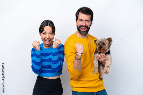 Young hispanic woman holding a dog isolated on white background celebrating a victory