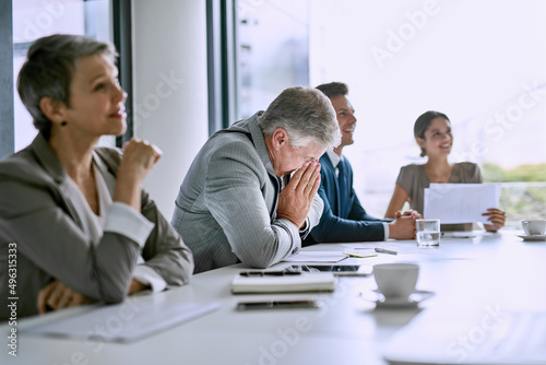 His sneezes are disrupting the meeting. Cropped shot of a businessman blowing his nose in the boardroom whilst in a meeting.