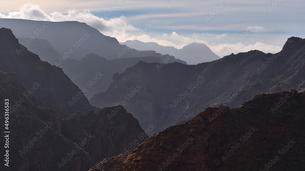 Panoramic view with landscape of the silhouettes of mountains in the west of Gran Canaria, Spain near road GC-210 on misty day with steep ravine.