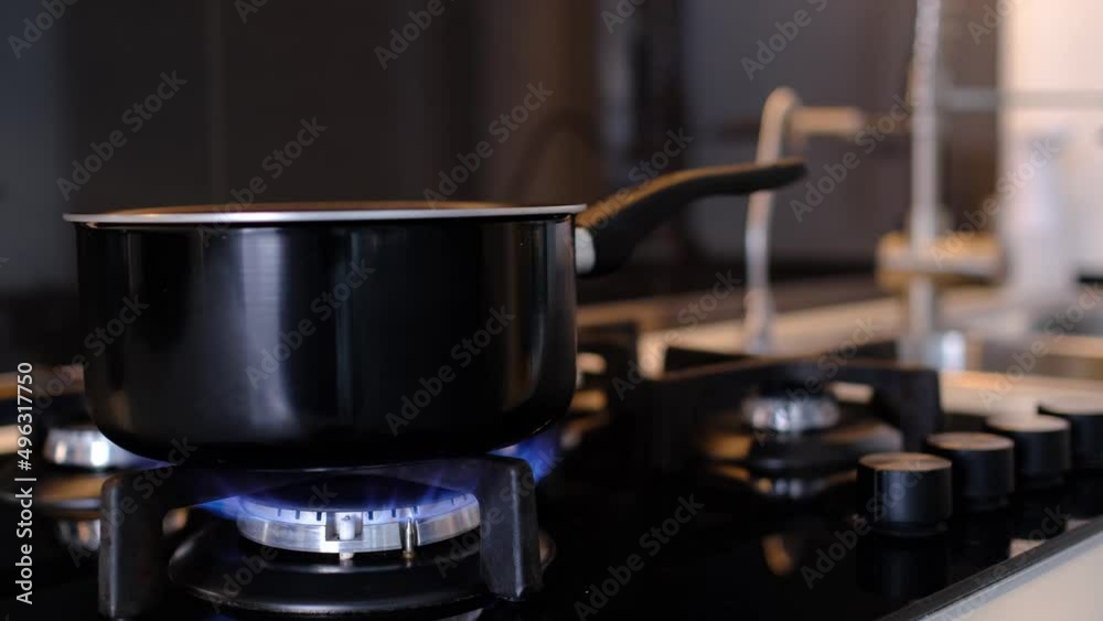 Closeup shot female hands puts pot on gas stove, turns on gas to cook lunch or dinner for whole family. Gas cooker with burning flames of propane gas. Closeup shot female hands puts pot on gas stove, turns on gas to cook lunch or dinner for whole family. Gas cooker with burning flames of propane gas.