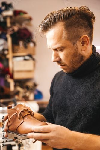 A  finished leather shoes in the hands of a master. Concept of cobbler artisan repairing and restoration work in shoe repair shop. photo