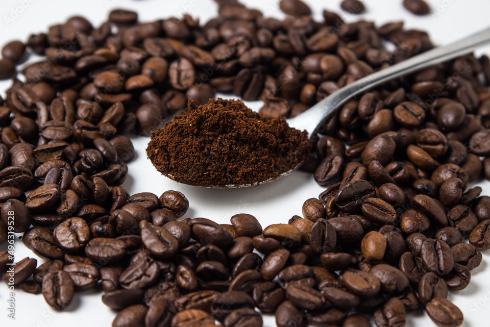 Fototapeta premium A spoon of ground coffee next to coffee beans on a white background. Roasted coffee beans. tonic drink