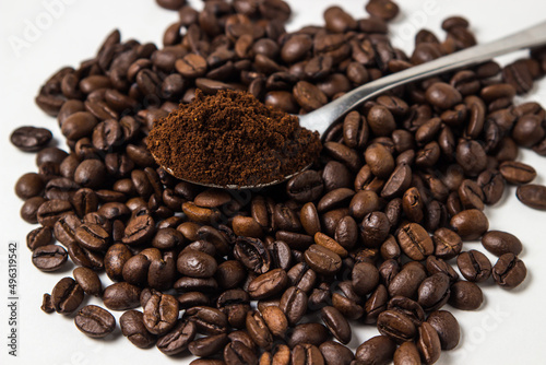 A spoon of ground coffee next to coffee beans on a white background. Roasted coffee beans. tonic drink