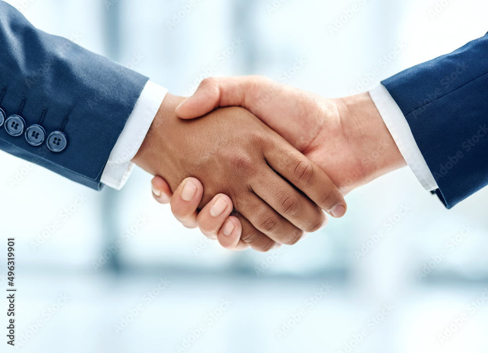We have a deal. Closeup shot of two businesspeople shaking hands together in an office.