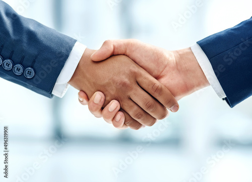 We have a deal. Closeup shot of two businesspeople shaking hands together in an office.