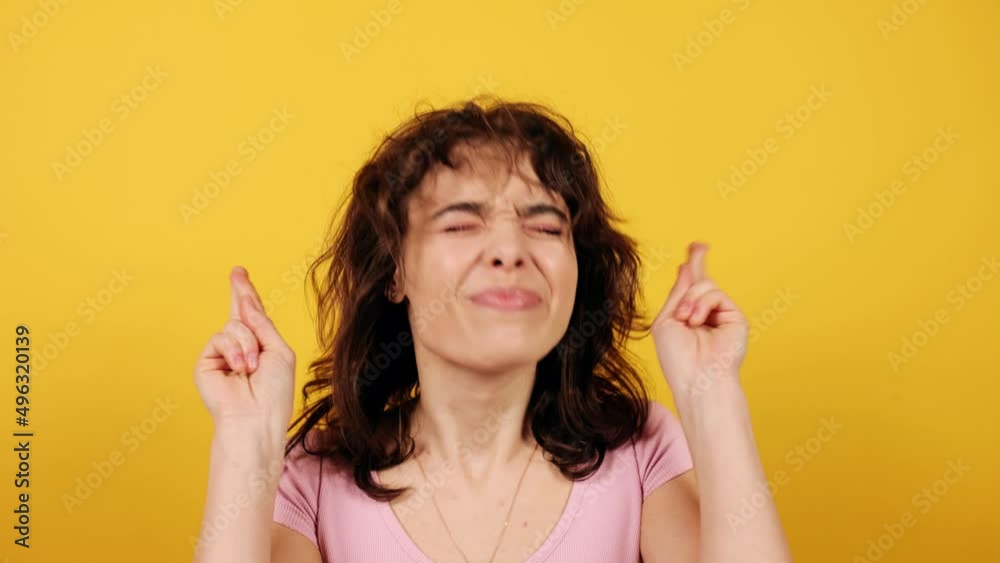 Portrait of lady crossing fingers on hands, make a wish. Attractive young girl on yellow background. Portrait of lady crossing fingers on hands, make a wish. Attractive young girl on yellow background.
