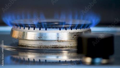 Brûleur d'une cuisinière à gaz qu'une main vient allumer puis éteindre en tournant un bouton