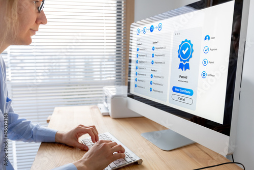 Quality Assurance (QA) and Control (QC) management. Standardization and certification concept. Compliance to international ISO standards. Manager or auditor looking at certificate on computer screen. photo