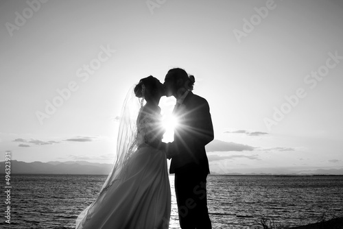 foto in bianco e nero di una coppia di sposi che si abbracciano in silhouette al tramonto