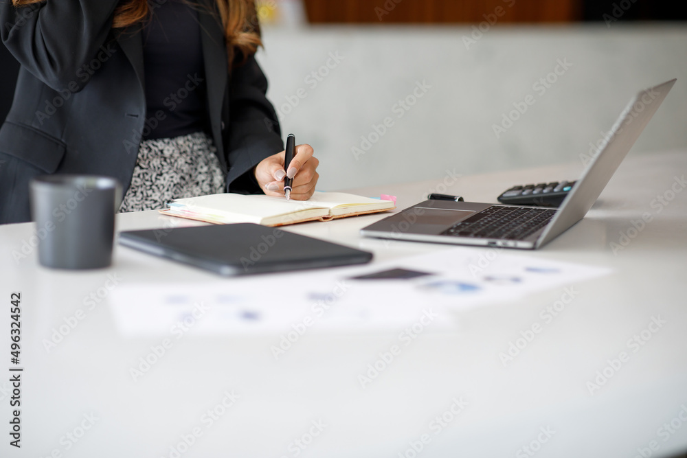 Close up of a woman hand writing in an agenda on a desk at home or office - obrazy, fototapety, plakaty 