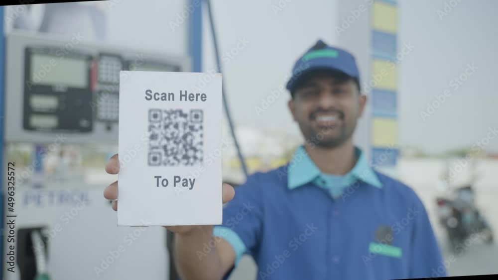 rack focus shot of petrol pump worker showing scan here to pay qr code for payment by looking at camera - concept of online or contact less payment at technology gas filling station.