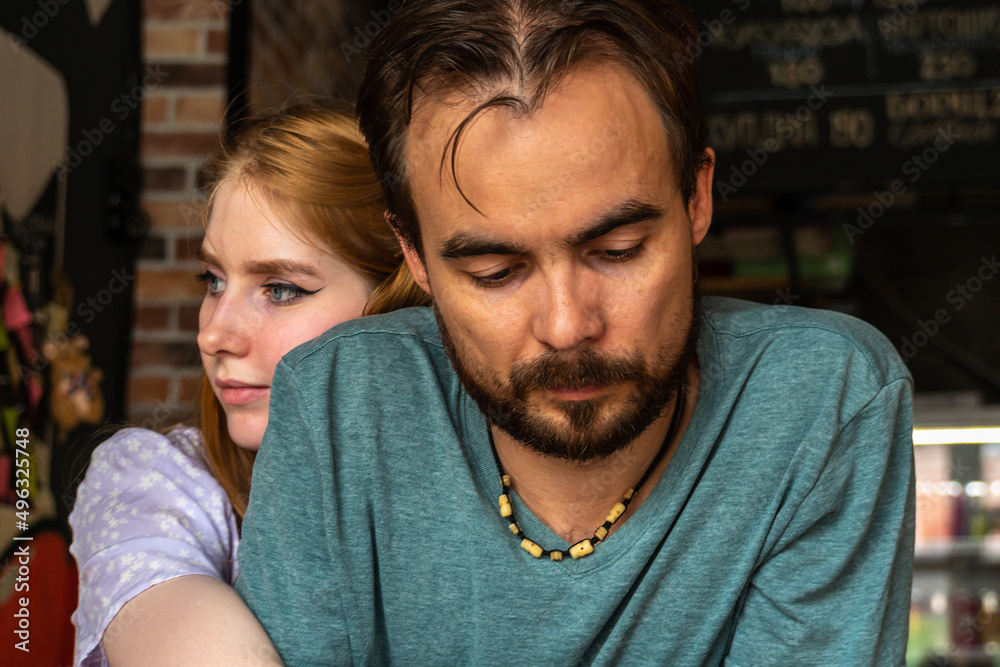 Thoughtful young couple hugging while sitting in bar and looking to distance. Set in bar. Thoughtful young couple hugging while sitting in bar and looking to distance. Set in bar.