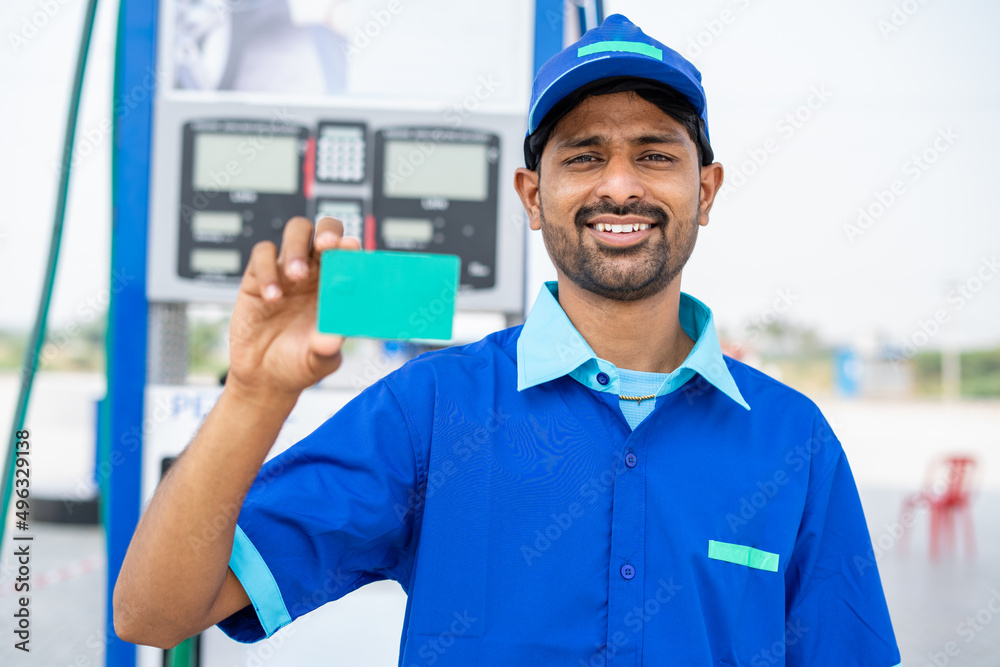 Smiling petrol pump worker showing green screen empty card by looking