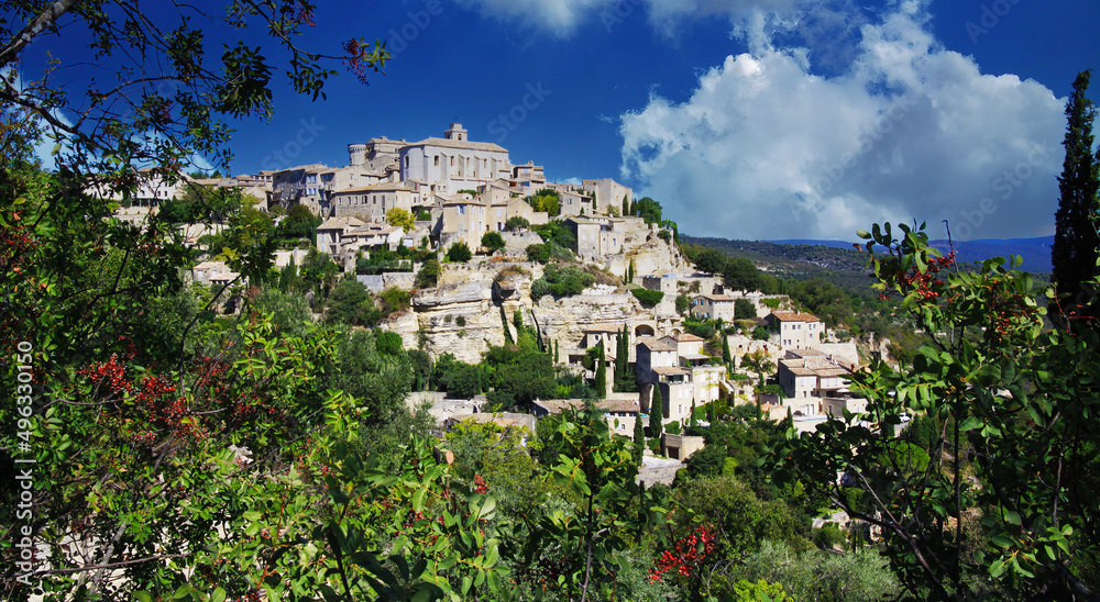 Scenic panoramic view on medieval picturesque old french village on hill top, blue summer sky, fluffy clouds - Gordes, Provence, France