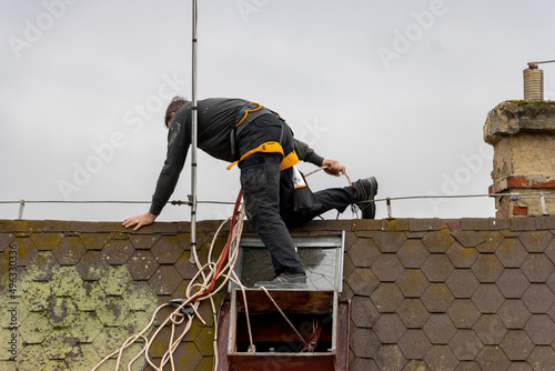 Bilde på lerret A man works on a roof with a skylight