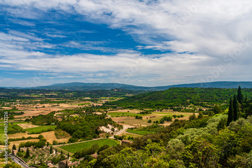 A small village with green fields under a cloudy sky in a sunny day in Avignon  Provence  France