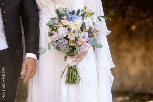 dettaglio di un bouquet di fiori tenuto in mano da una sposa con accanto il suo sposo  photo