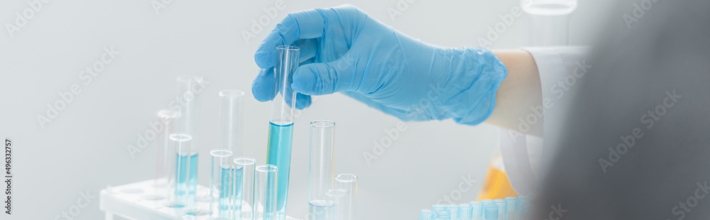 partial view of scientist holding test tube with blue liquid, banner. partial view of scientist holding test tube with blue liquid, banner.