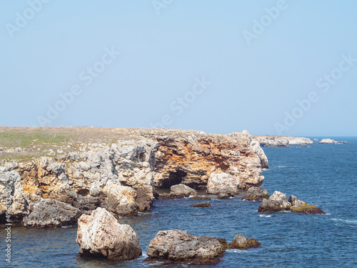 Rocks at sea beach. Ocean bay rock beach scene. Mountains with caves on Tyulenovo, Bulgaria photo