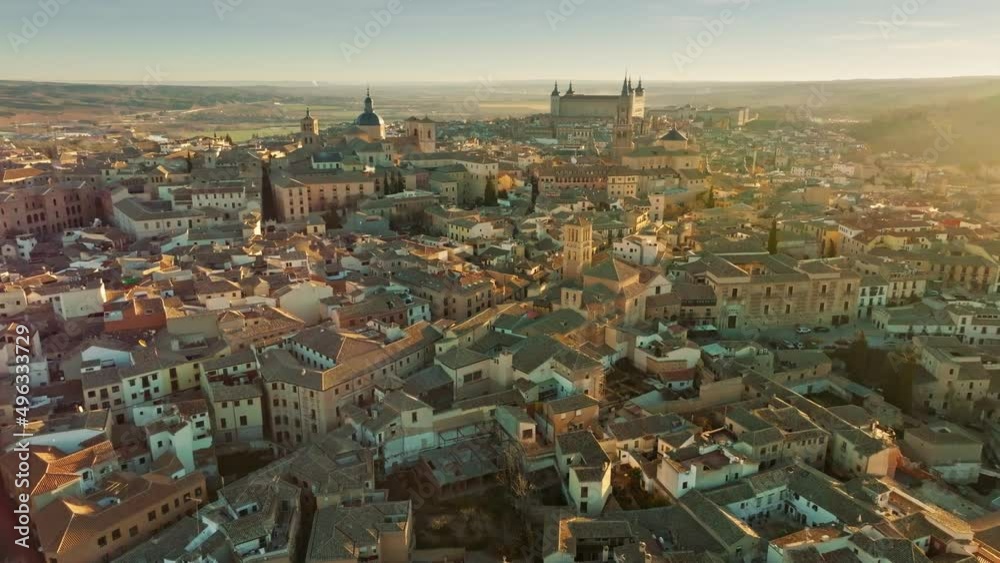 Flight over houses and cathedral in Toledo at sunset. Aerial view of Toledo, Castilla-La Mancha, Spain