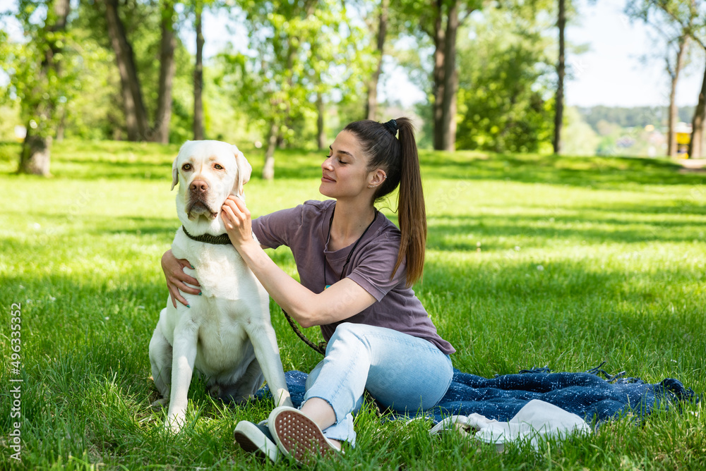 Young beautiful woman in the park with her pet dog white Labrador Retriever that she adopt from the pet shelter to give him good life and love. Female animal lover with her adopted puppy having fun. Young beautiful woman in the park with her pet dog white Labrador Retriever that she adopt from the pet shelter to give him good life and love. Female animal lover with her adopted puppy having fun.